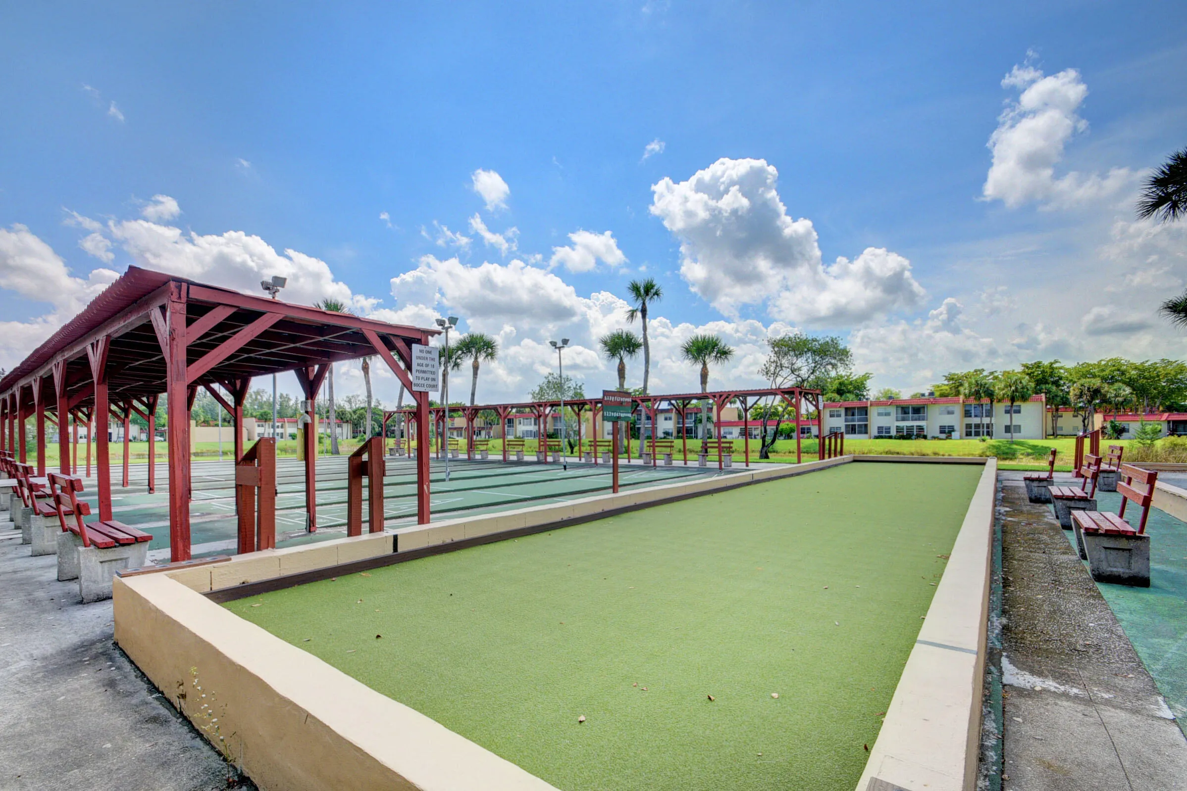 Bocce ball court featuring turf playing surfaces, concrete borders, and a wood-framed pergola with built-in benches