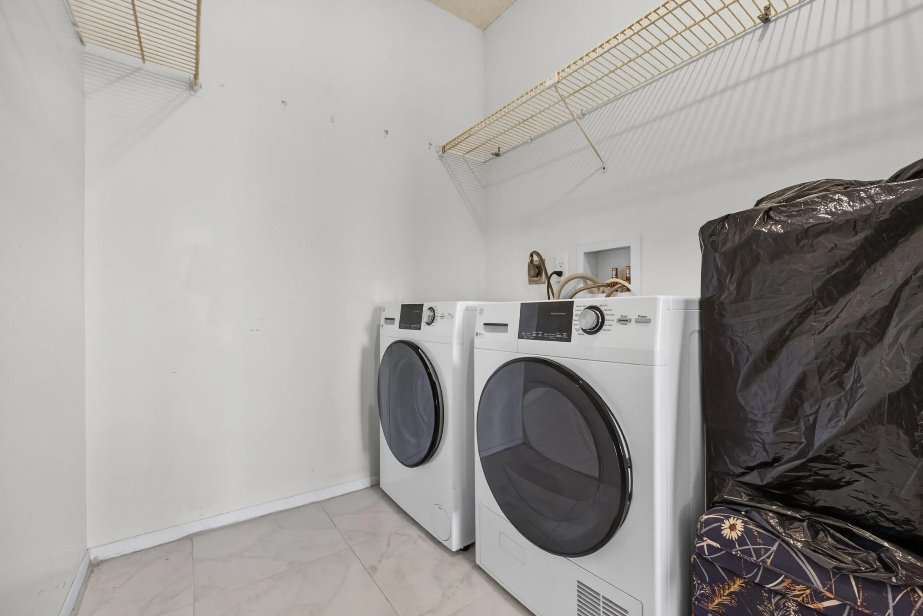 Dedicated laundry area featuring wire shelving, white tile flooring
