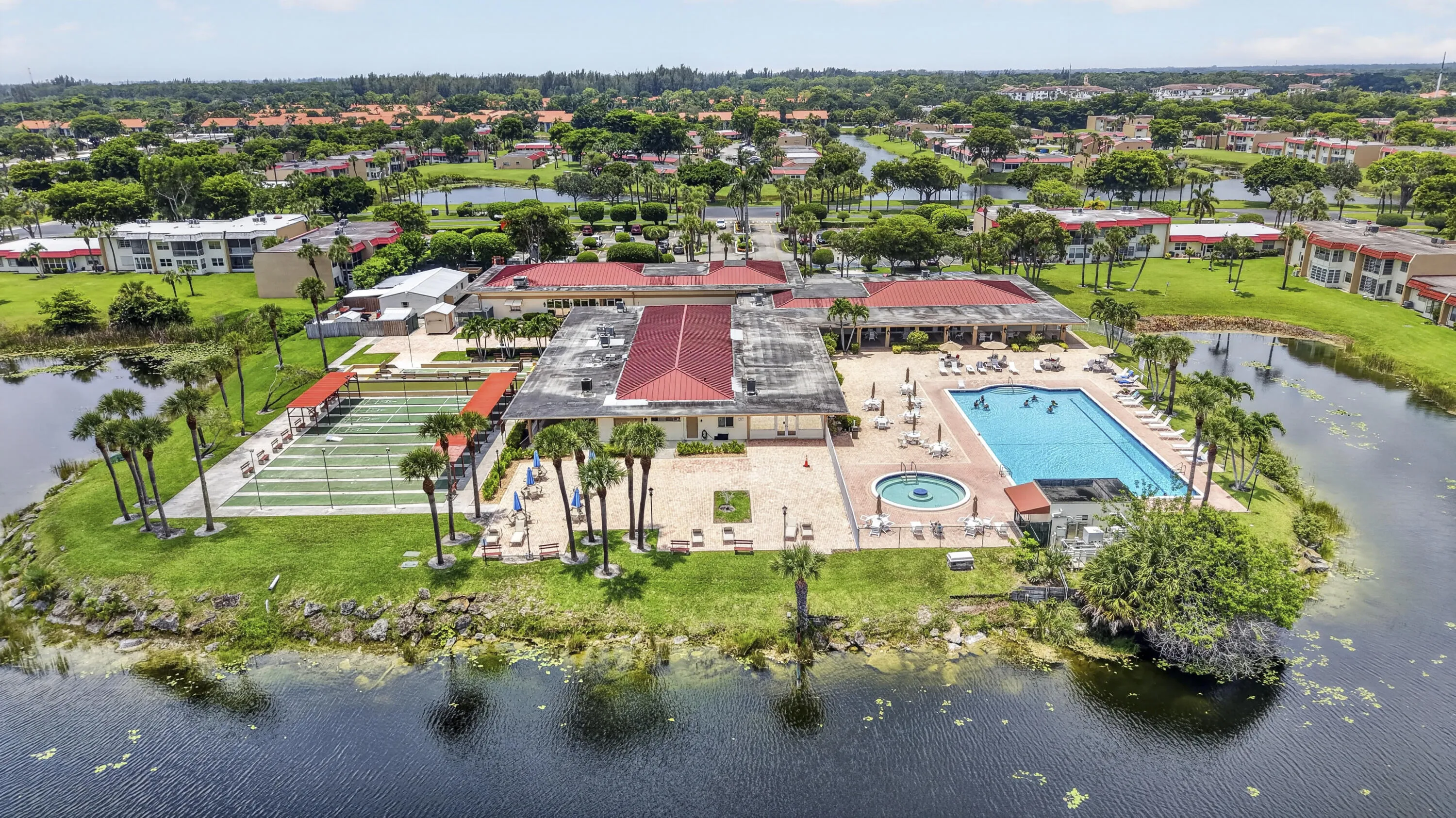 Expansive recreation area featuring multiple tennis courts, a large swimming pool, a circular spa, and a surrounding paver deck with lounge seating