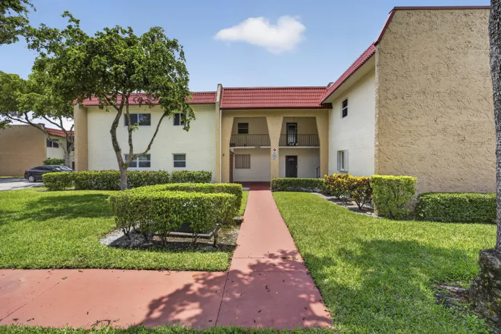 Two-story stucco building featuring a red tile roof and multiple units