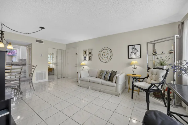 Spacious living area featuring neutral wall tones, large-format tile flooring, and a mirrored closet system