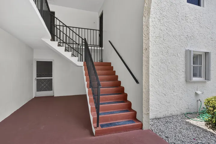 Exterior concrete staircase with black metal railings and a red-painted finish