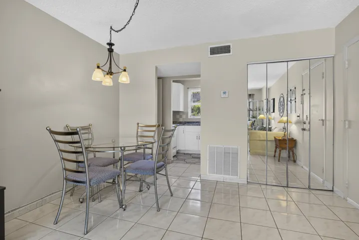 Dining area featuring tile flooring, a chandelier, and mirrored closet doors