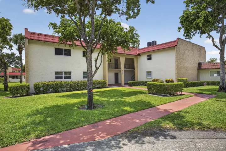 Two-story building featuring a stucco exterior, red tile roofing, and multiple windows