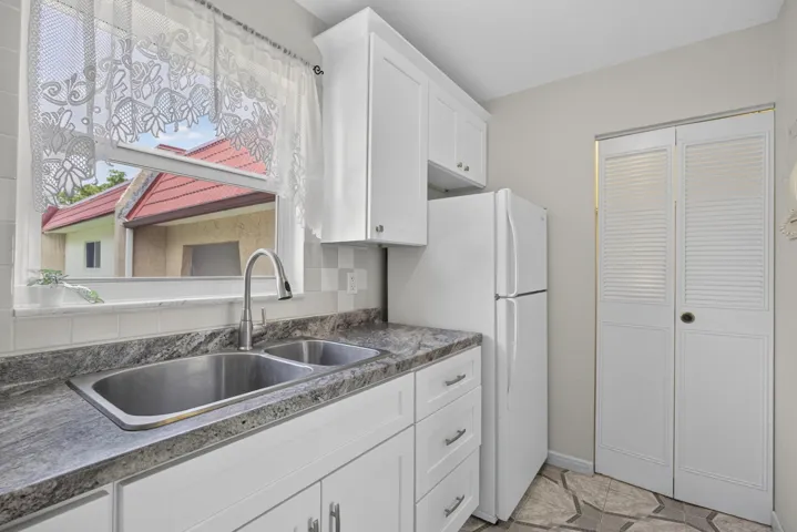 Kitchen featuring white cabinetry, a dual basin stainless steel sink with a high-arc faucet, and granite-look countertops