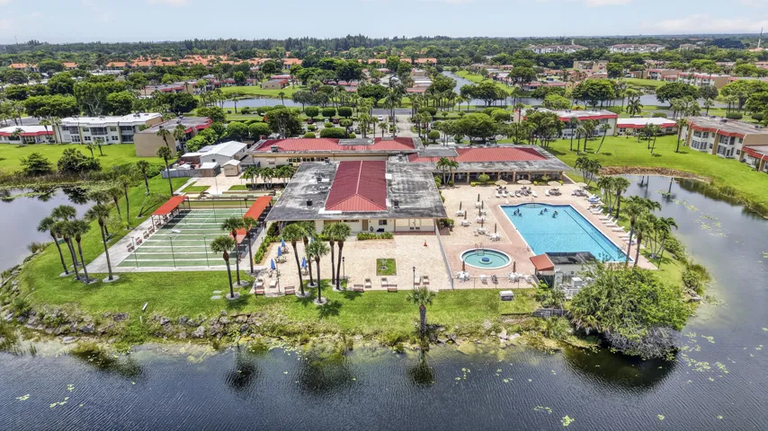 Expansive recreation area featuring multiple tennis courts, a large swimming pool, a circular spa, and a surrounding paver deck with lounge seating