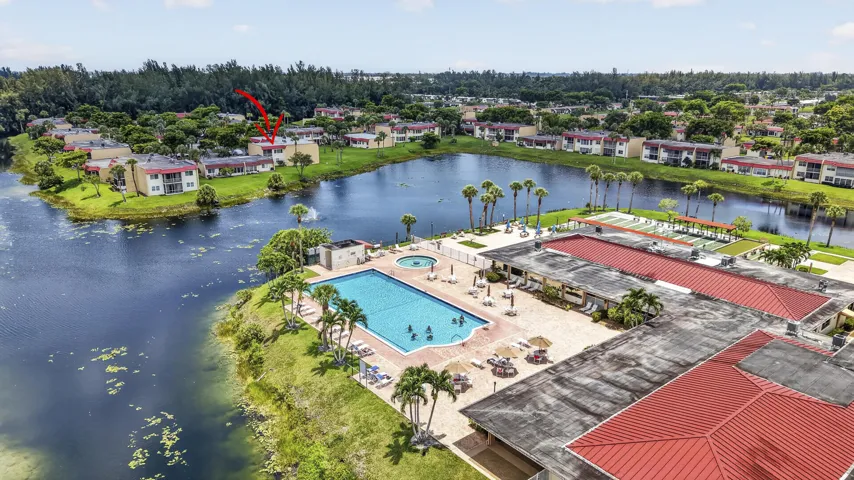 Community pool area with a large swimming pool, surrounding patio, and shuffleboard courts
