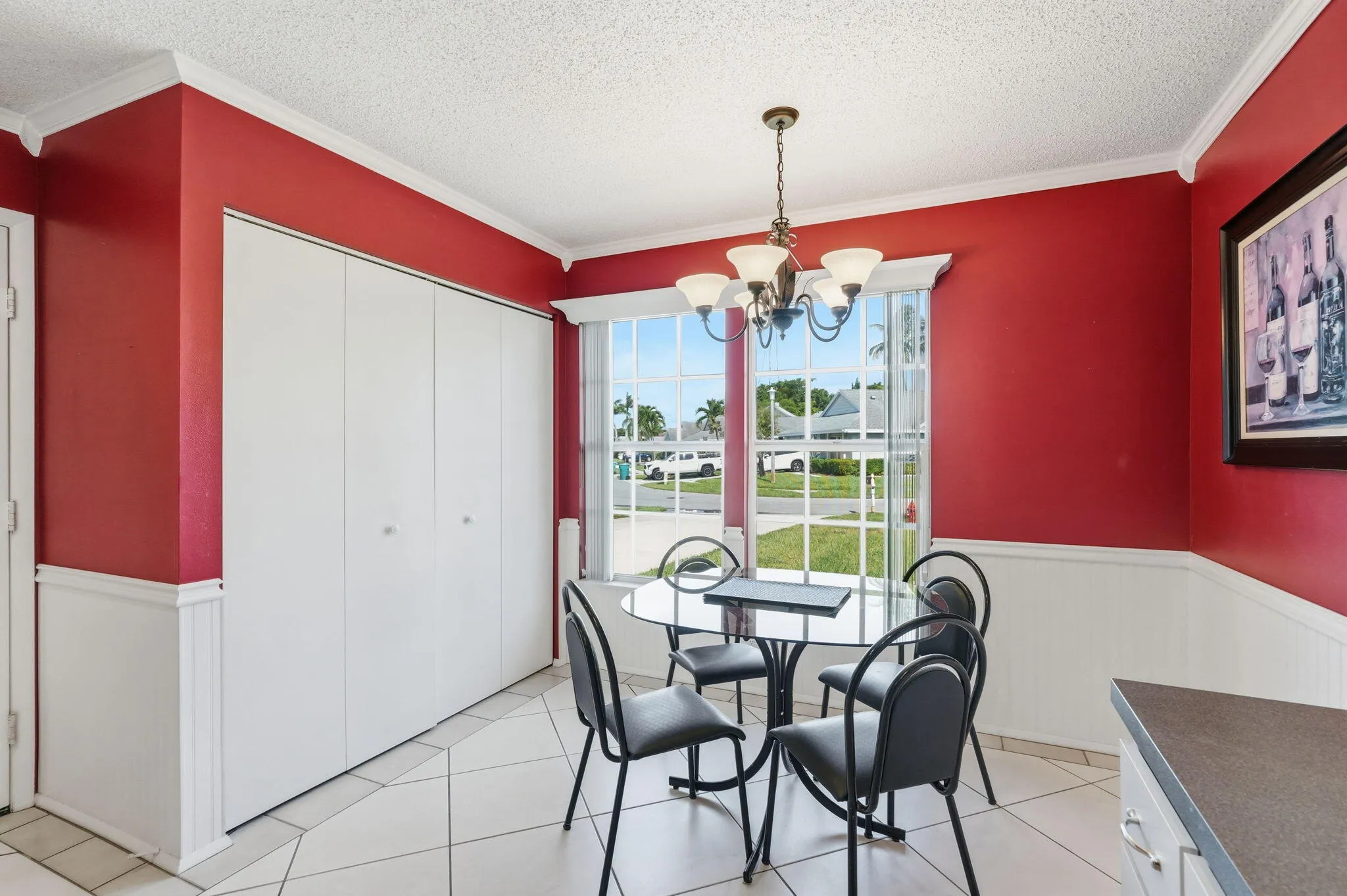 Dining area featuring a chandelier, large window, tile flooring, and wainscoting