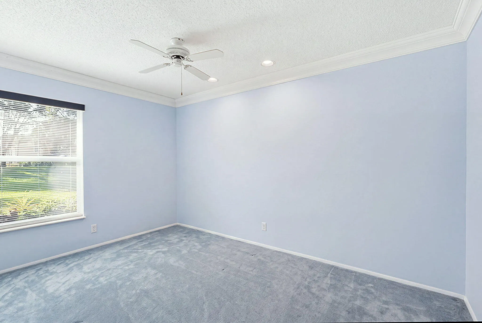 Room featuring light blue walls, light blue carpet, crown molding, and a ceiling fan with integrated lighting