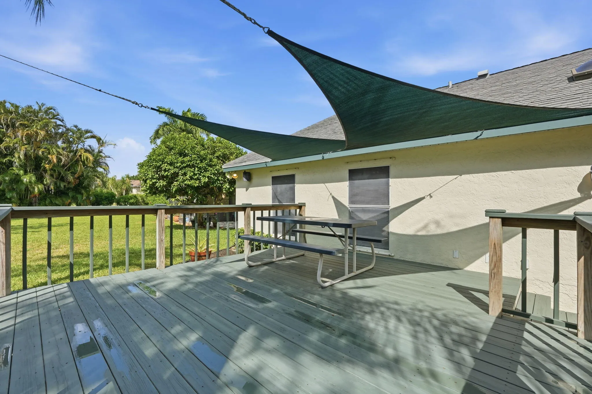 Outdoor wood deck with a partial shade sail installation