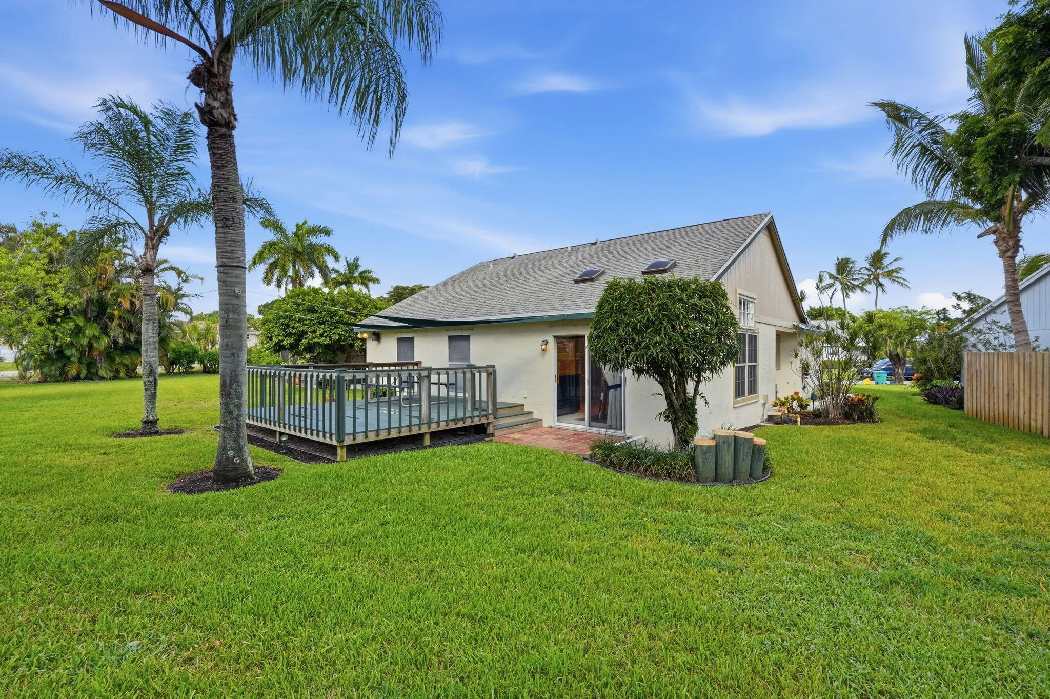 Expansive green lawn with a wooden deck and privacy fencing