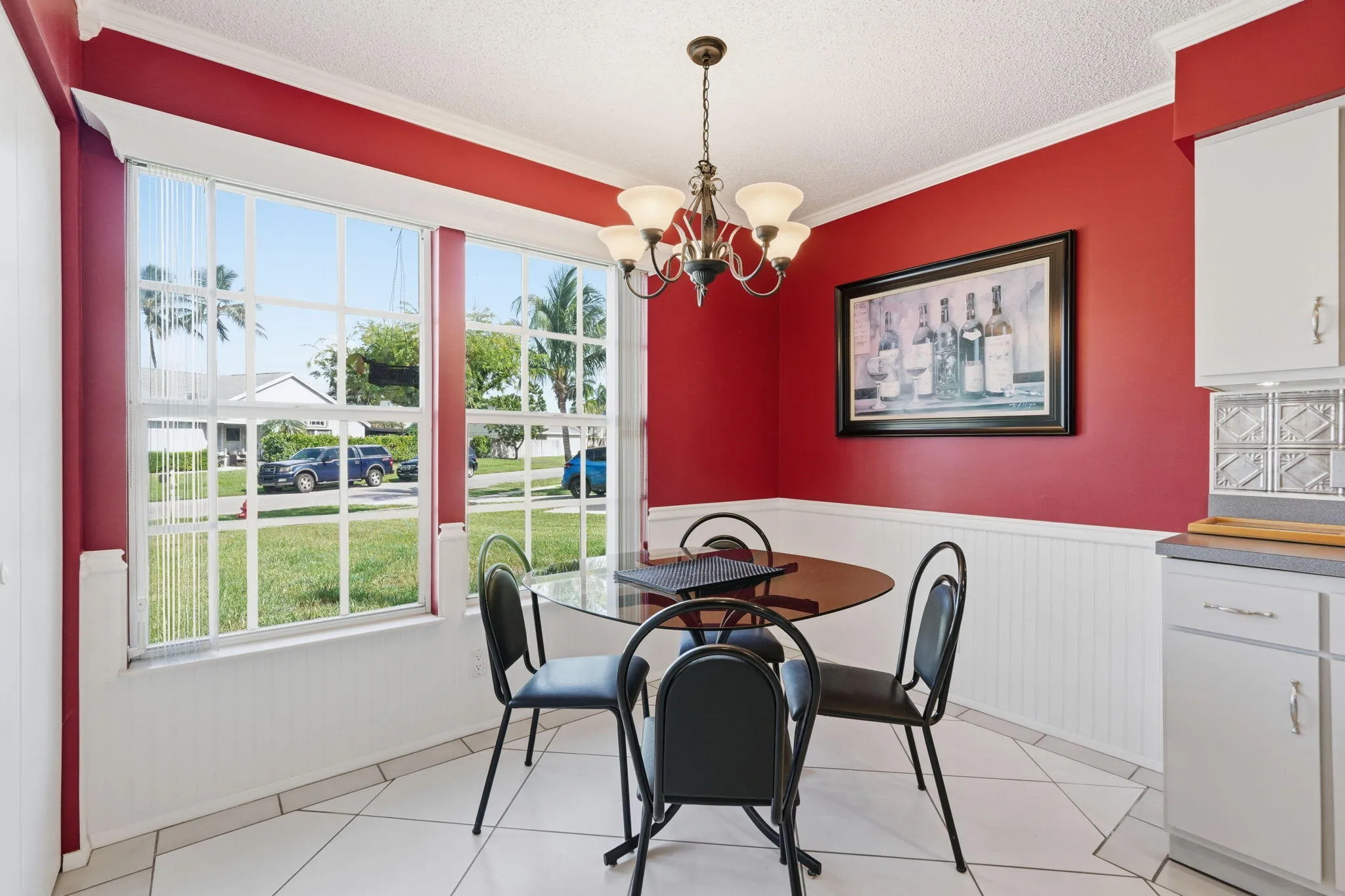 Bright dining area featuring dual large windows, crown molding, white beadboard wainscoting, and a ceiling-mounted chandelier