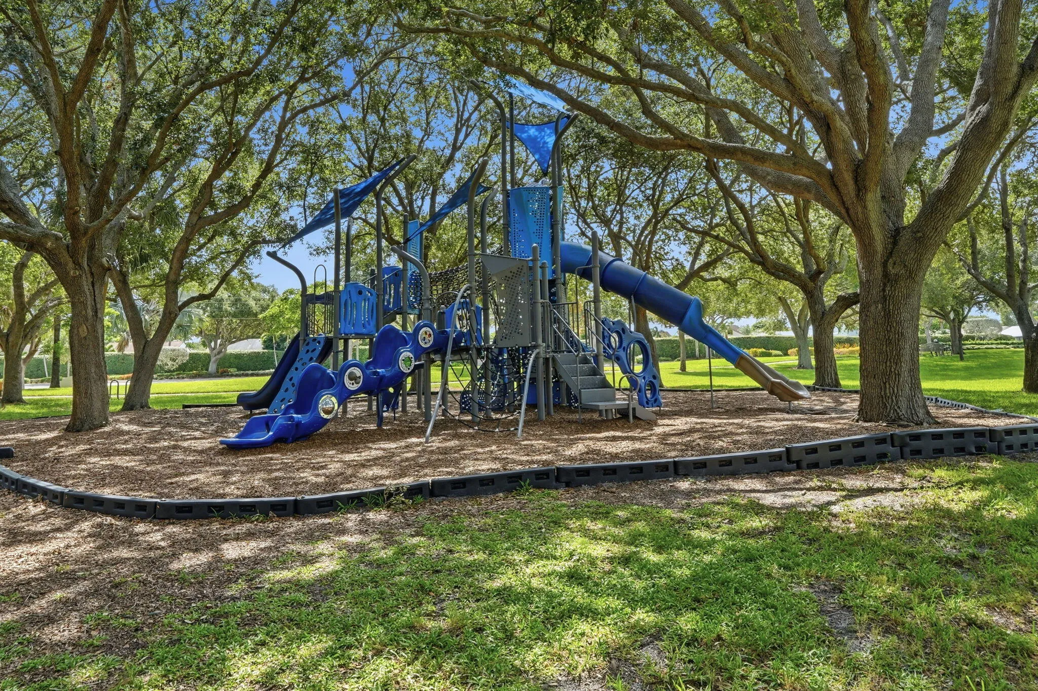 Community playground featuring a multi-level play structure with multiple slides and climbing elements