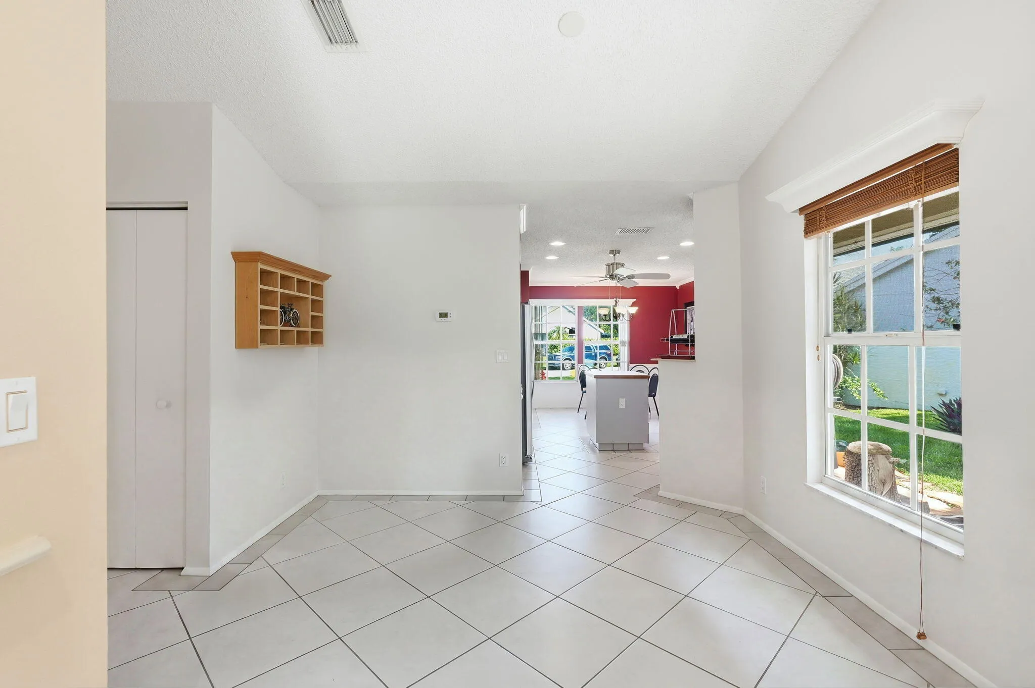 Bright dining area featuring diagonal tile flooring, a large window with crown molding, and a built-in wall shelf