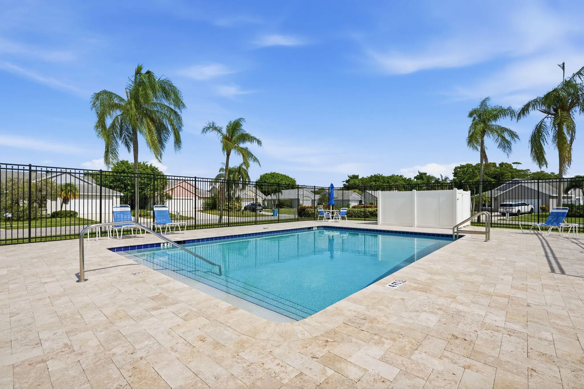 Rectangular swimming pool featuring integrated steps, stainless steel handrails, and a perimeter of light-toned paver decking