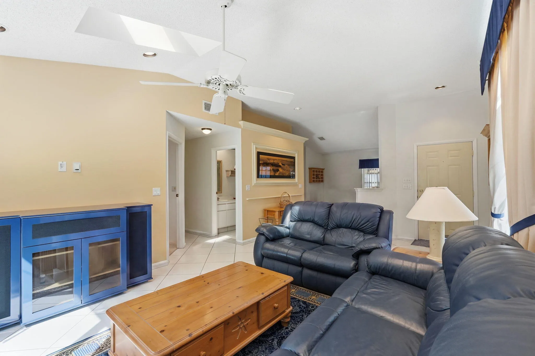 Vaulted ceiling living area featuring a ceiling fan, recessed lighting, and skylights