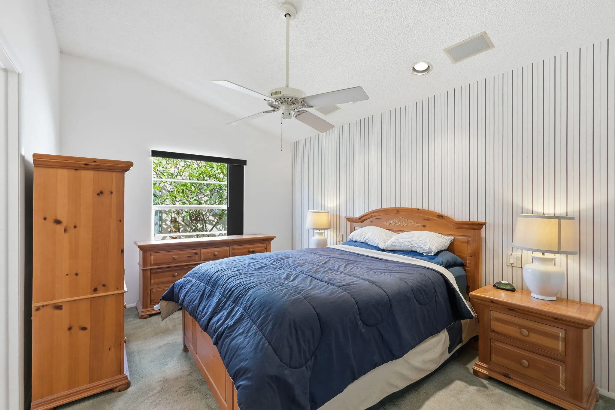 Vaulted ceiling bedroom with a ceiling fan, recessed lighting, and a window