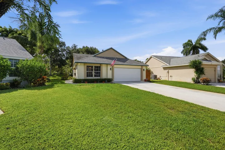 Single-story residence featuring a two-car garage, concrete driveway, and a well-maintained lawn