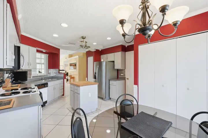 Spacious kitchen featuring white cabinetry, stainless steel appliances, a center island with butcher block countertop, and tile flooring