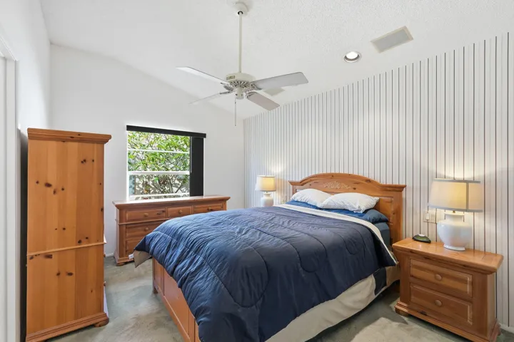 Vaulted ceiling bedroom with a ceiling fan, recessed lighting, and a window