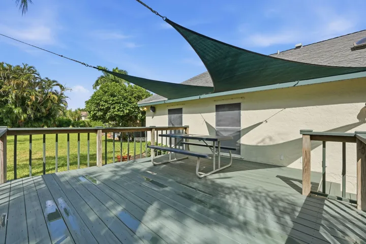 Outdoor wood deck with a partial shade sail installation