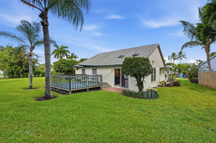 Expansive green lawn with a wooden deck and privacy fencing