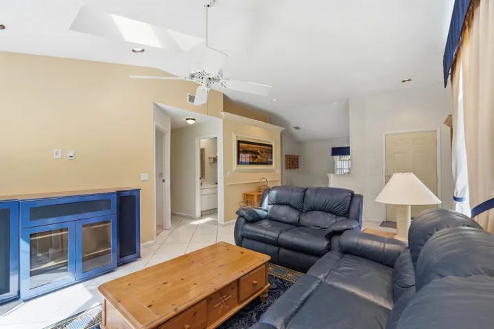 Vaulted ceiling living area featuring a ceiling fan, recessed lighting, and skylights