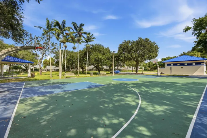 Outdoor basketball court featuring green and blue surface colors and white court lines