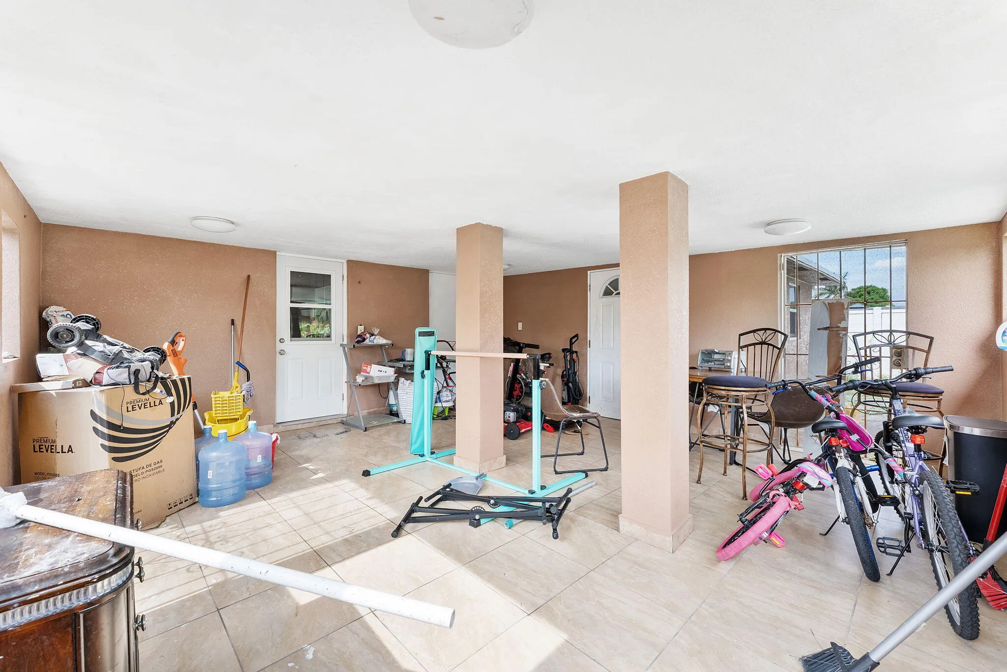 Spacious covered patio featuring tiled flooring, multiple overhead light fixtures, and exterior access points