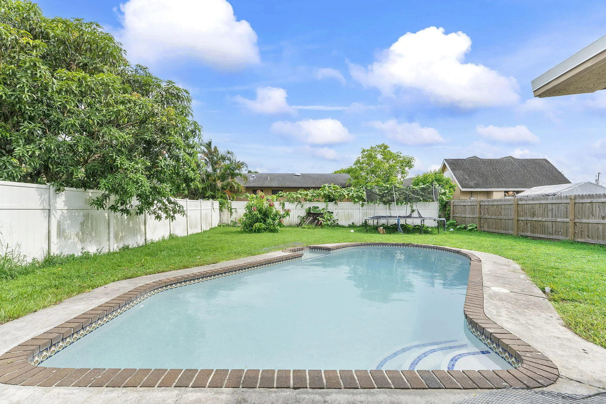 In-ground swimming pool with brick coping and integrated steps