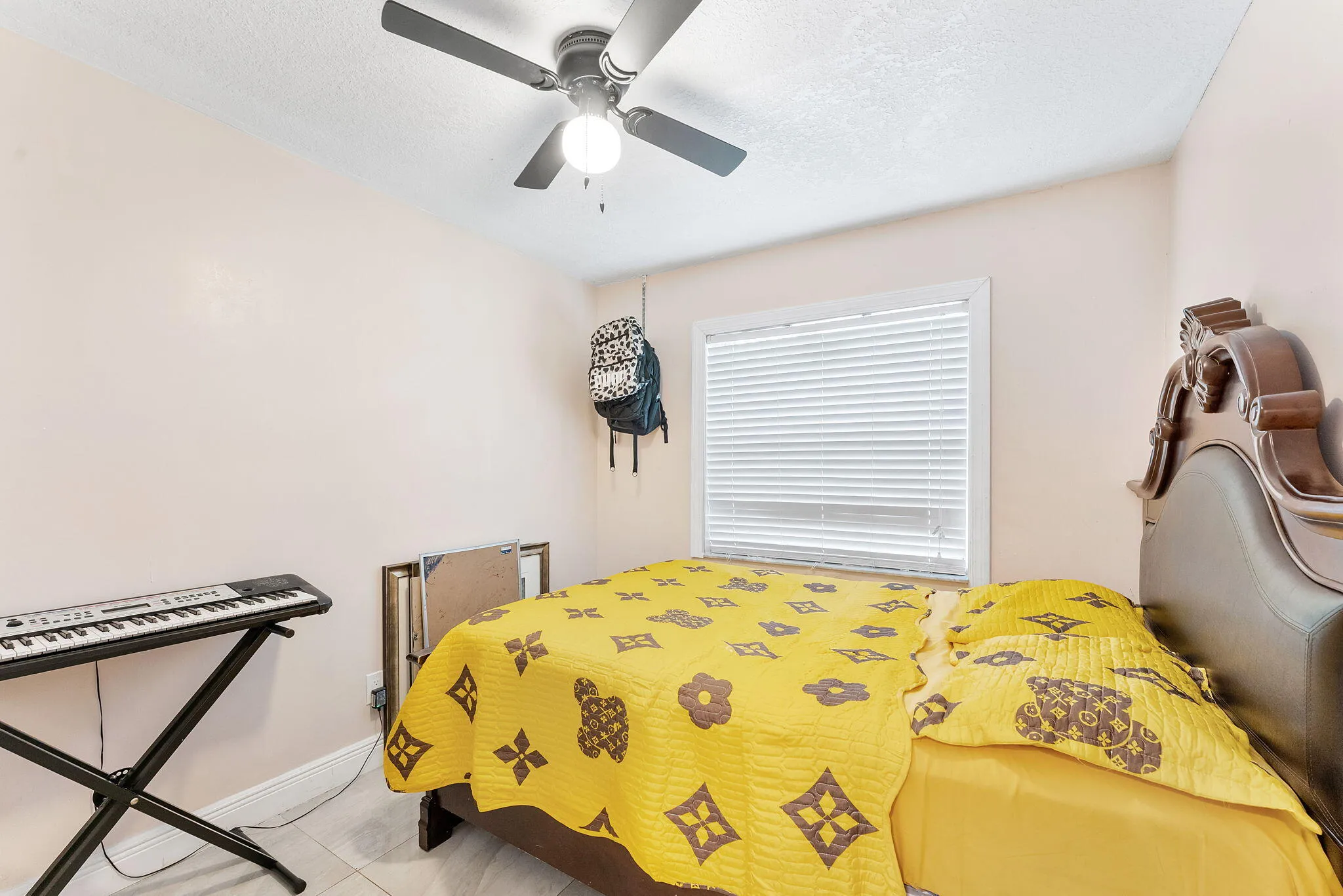 Bedroom featuring a window with horizontal blinds, light-toned walls, and a ceiling fan with integrated lighting