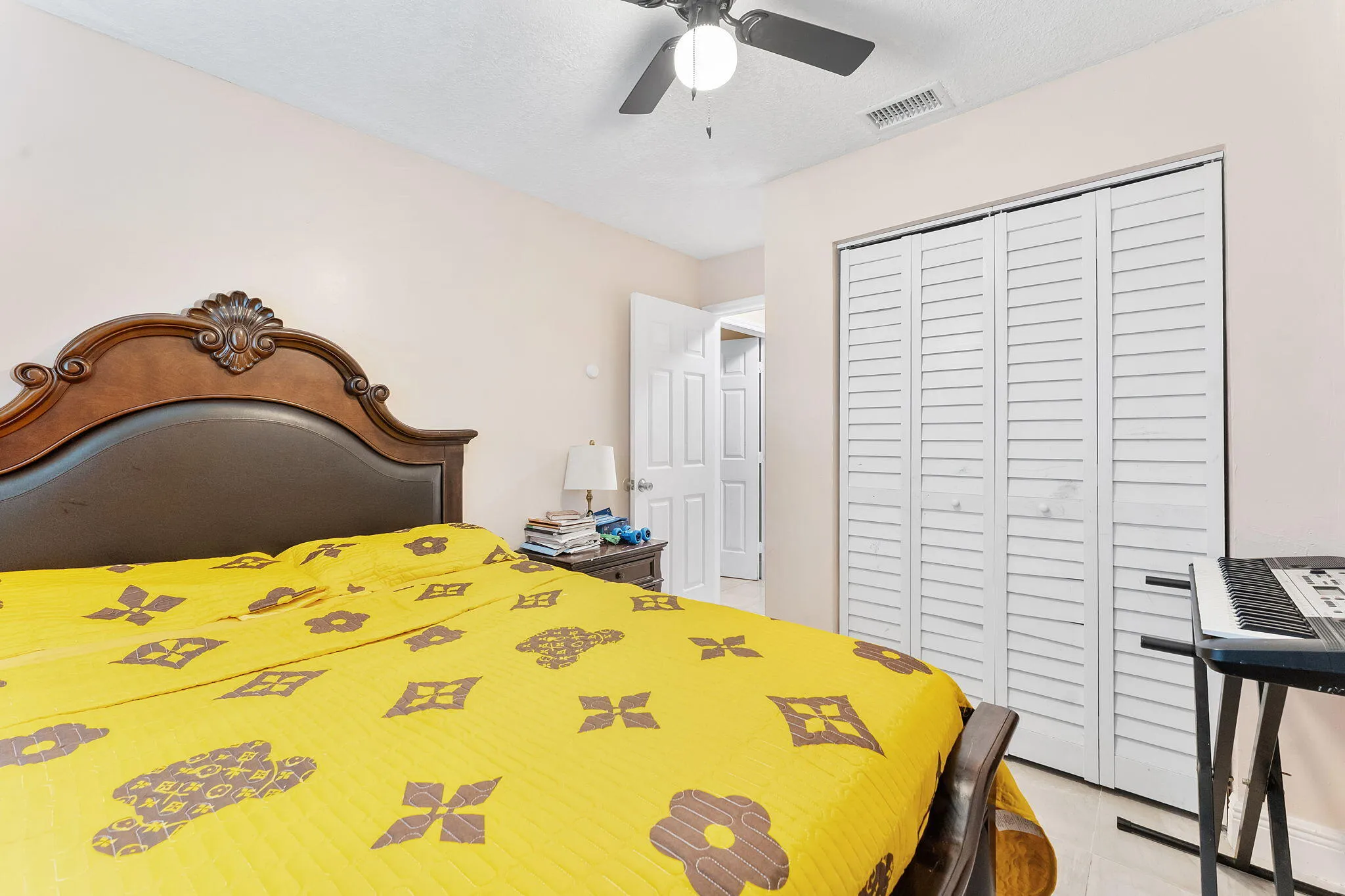 Louvered bi-fold closet doors, ceiling fan with light fixture, and wood-finish flooring