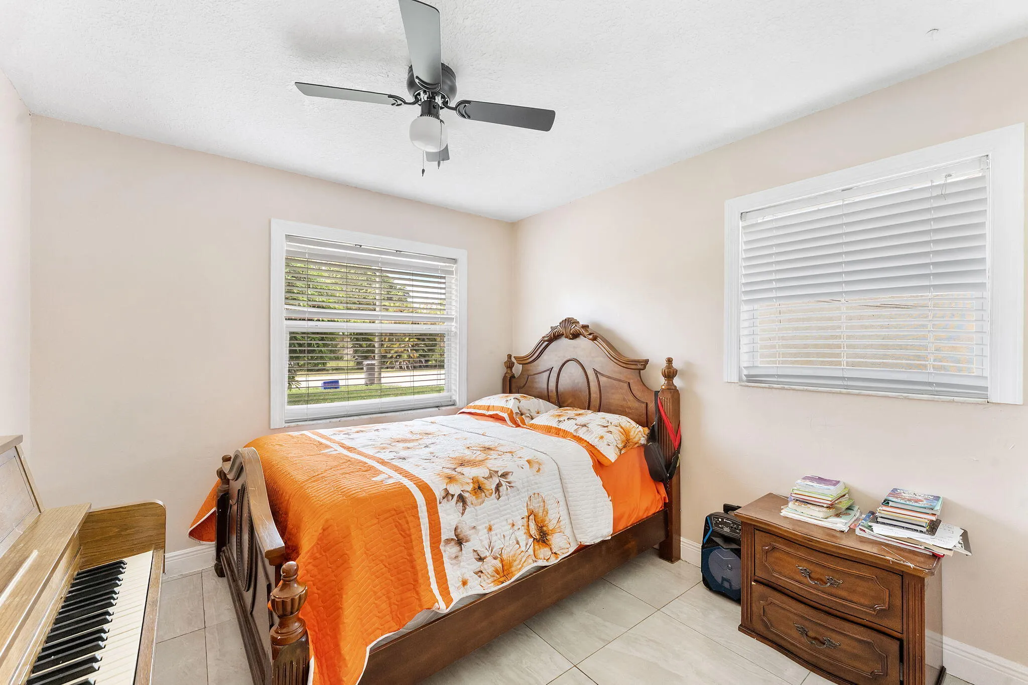 Room featuring light-toned walls, tile flooring, and two windows with blinds