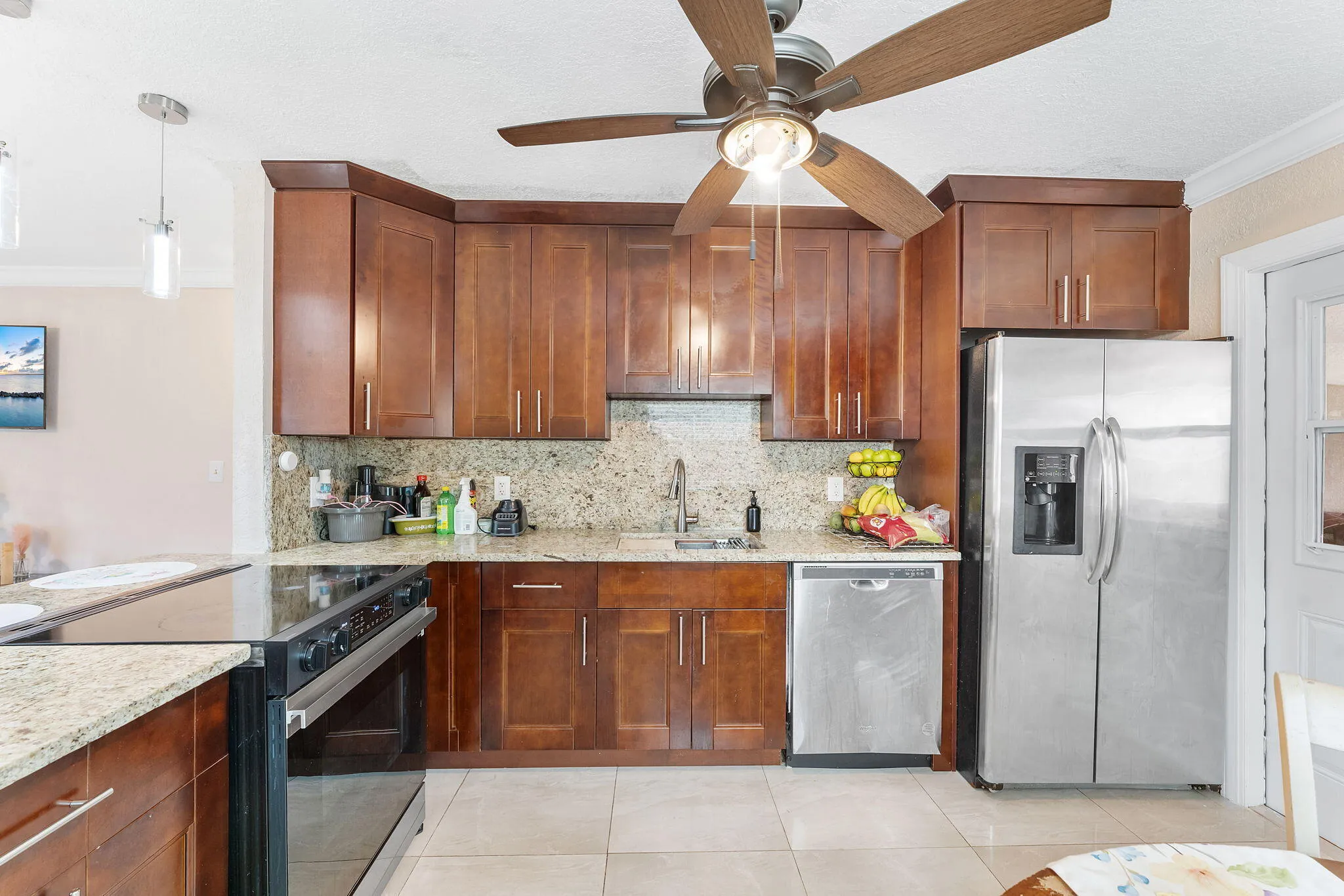 Kitchen featuring wood cabinetry, granite countertops, stainless steel appliances, and tile flooring