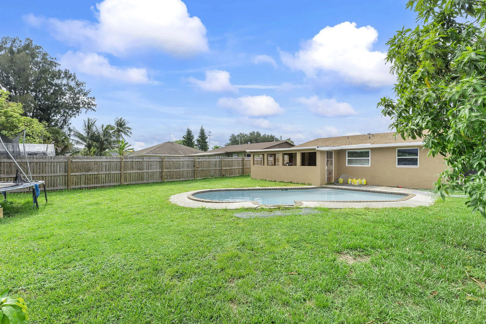 Spacious backyard featuring a fenced perimeter, a freeform inground pool, and a screened patio