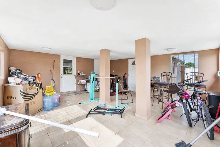Spacious covered patio featuring tiled flooring, multiple overhead light fixtures, and exterior access points
