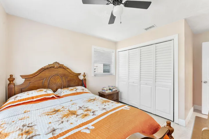 Bedroom featuring a ceiling fan, window with blinds, and white bi-fold closet doors