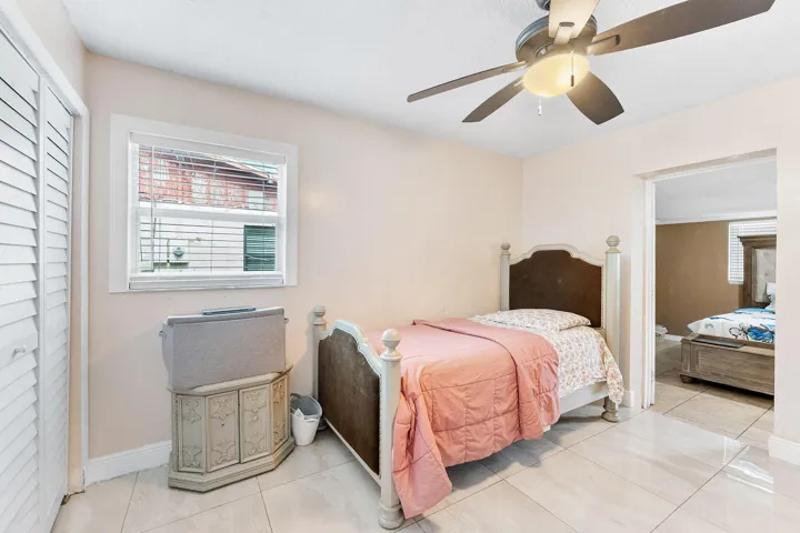 Bedroom featuring light-toned walls, tile flooring, and a ceiling fan with integrated lighting