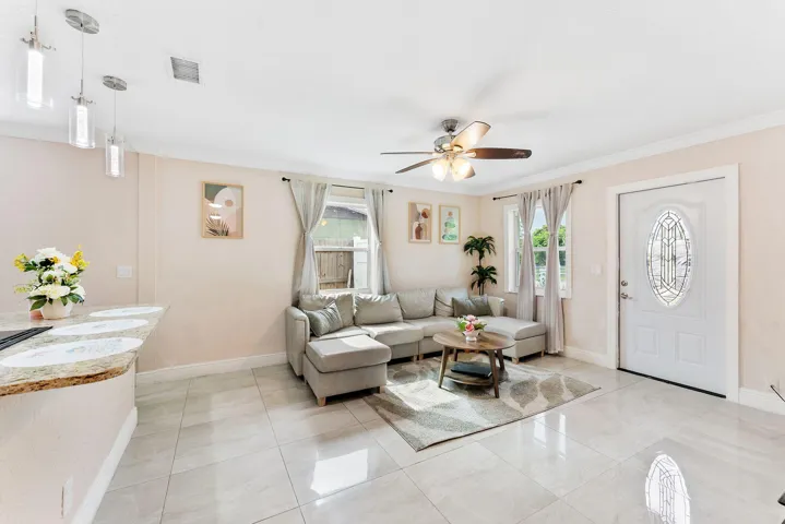 Open-concept living area featuring light-toned tile flooring, recessed lighting, and a ceiling fan