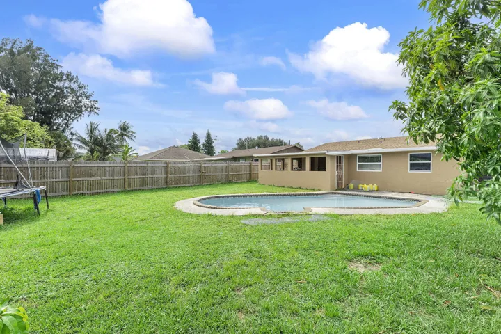 Spacious backyard featuring a fenced perimeter, a freeform inground pool, and a screened patio