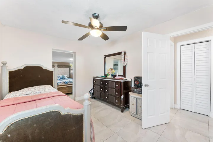 Neutral tile flooring extending throughout, ceiling fan with integrated lighting, and a white six-panel interior door