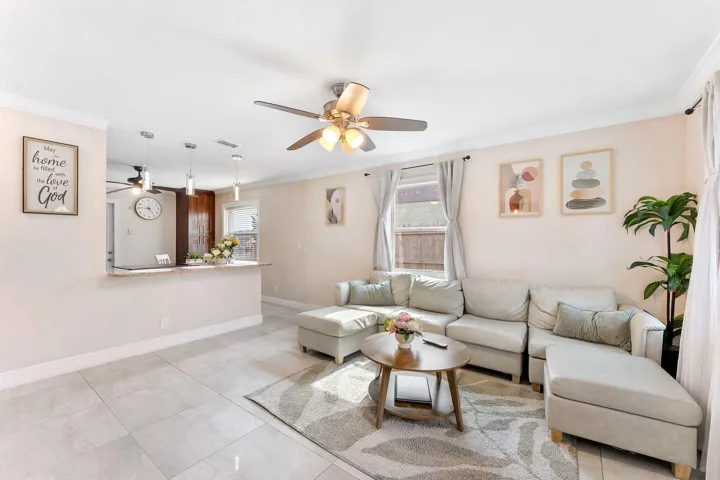 Living area featuring light-toned tile flooring and a ceiling fan with integrated lighting