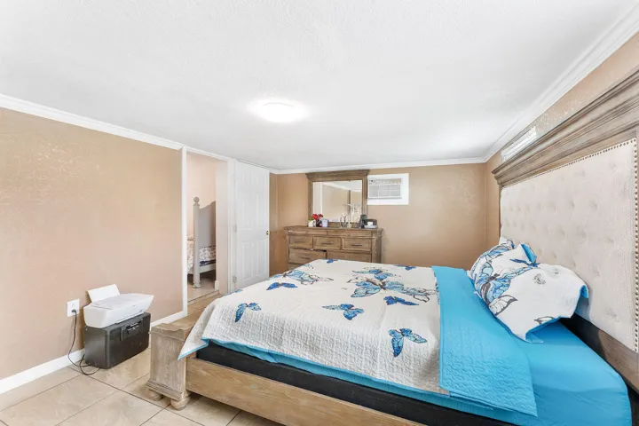 Bedroom featuring neutral wall tones, crown molding, tile flooring, and a large window