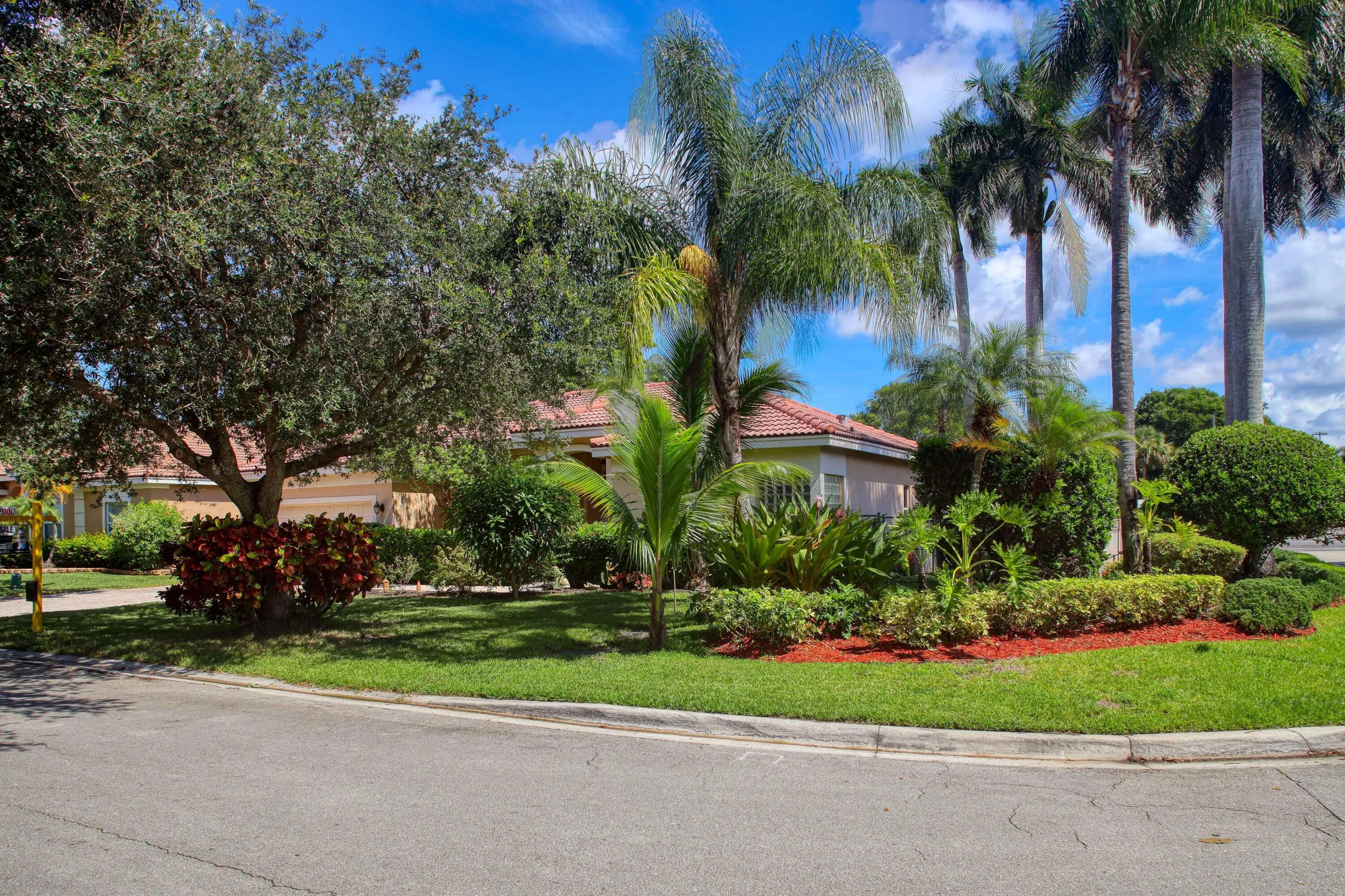Premium corner lot showcasing tropical landscaping and attractive streetscape in the desirable Yardley Estates community.