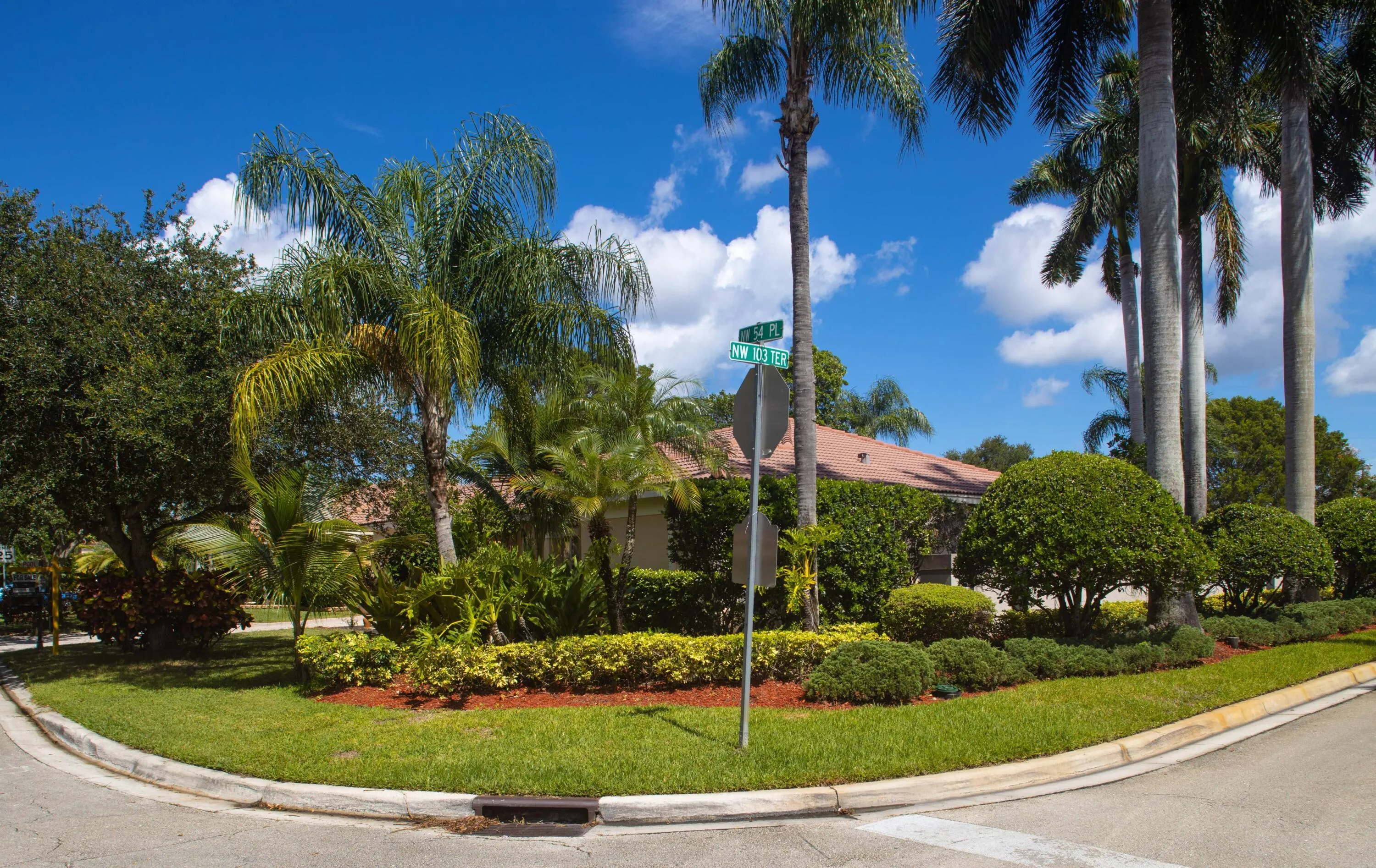 Beautifully landscaped corner lot with mature palm trees, lush tropical plantings, and exceptional curb appeal.