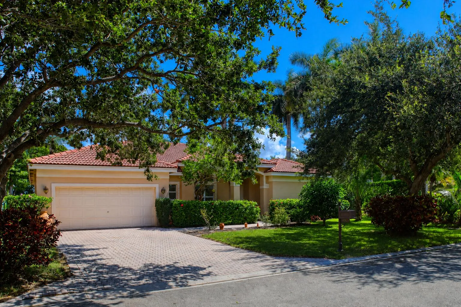 Attractive front elevation surrounded by mature oak trees and professionally maintained tropical landscaping.