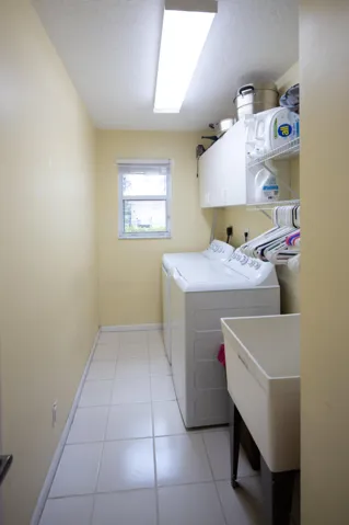 Separate laundry room with utility sink, storage space, and newer washer and dryer for added convenience.