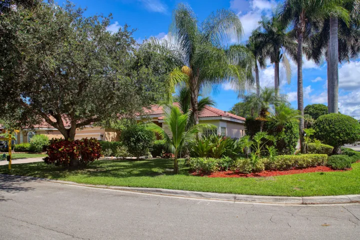 Premium corner lot showcasing tropical landscaping and attractive streetscape in the desirable Yardley Estates community.