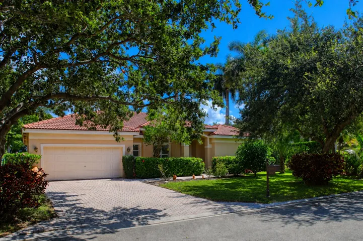 Attractive front elevation surrounded by mature oak trees and professionally maintained tropical landscaping.