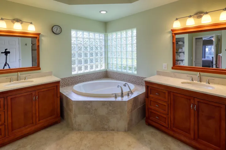 Spa-inspired primary bath with Roman soaking tub, dual vanities, and elegant finishes throughout.